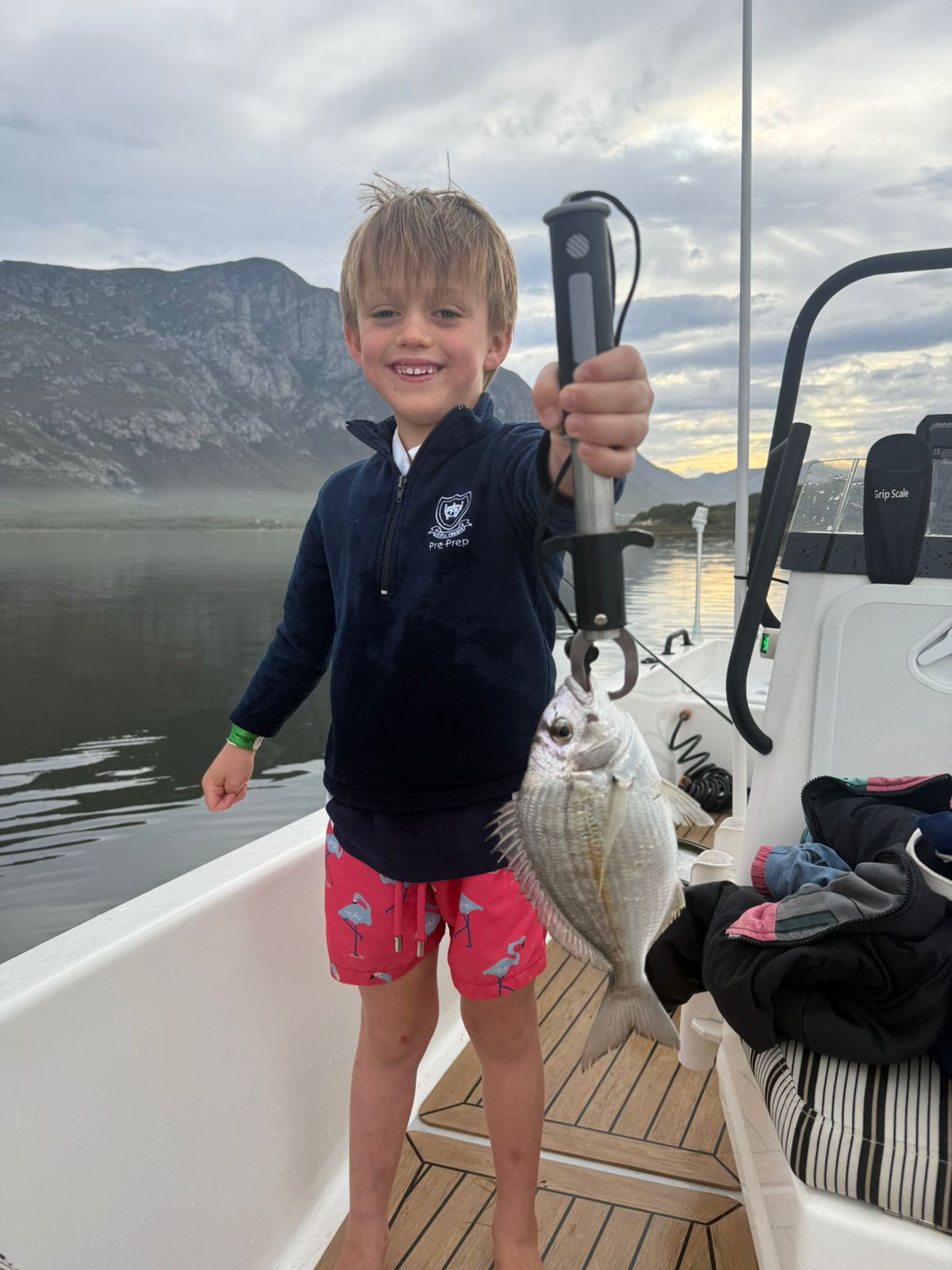 Young boy proudly holding up a fish caught in the lagoon